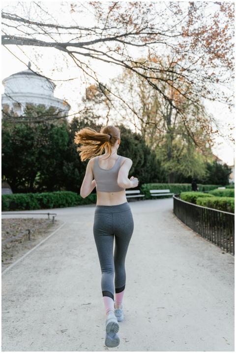 Back view of a woman jogging in a park, promoting