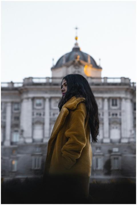Stylish woman in a coat poses by a historic buildi