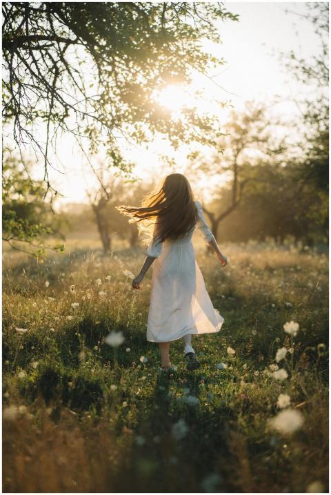 A young woman in a white dress running joyfully th