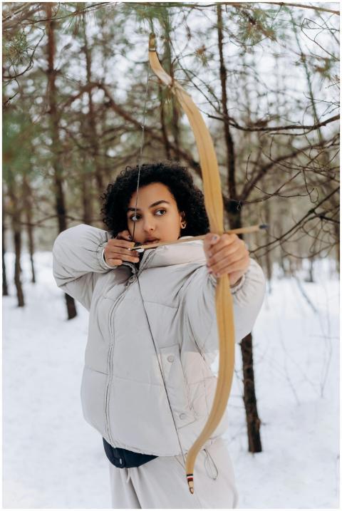 A woman aiming an arrow in a snowy forest, capturi