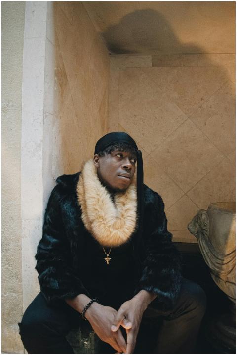 African American man in fur coat sitting indoors i