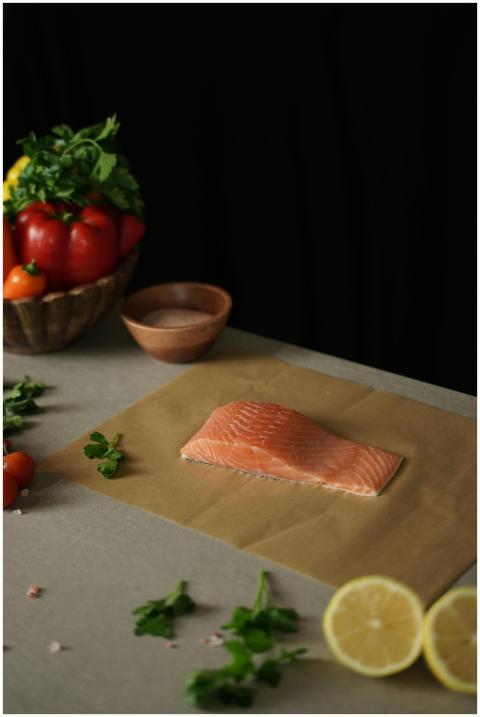 A fresh salmon fillet on parchment paper with herb