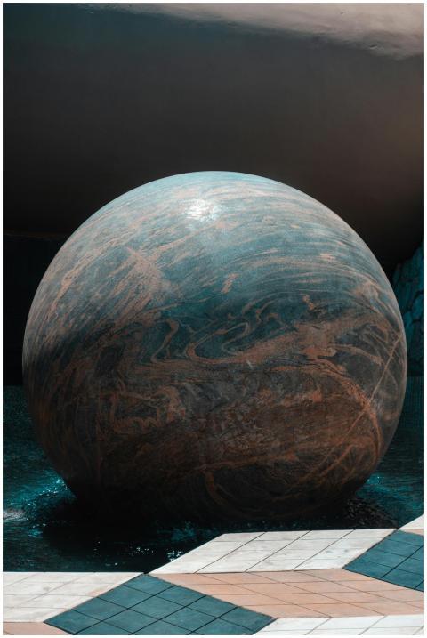 A large stone sphere with artistic patterns in a m