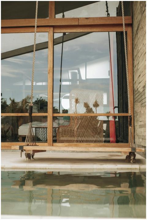 Stylish indoor swing by the pool with a glass refl