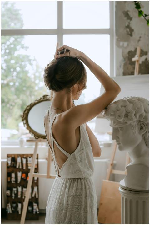 A woman in a white dress poses gracefully beside a