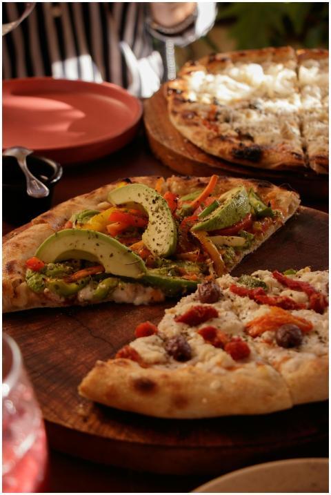 Close-up of gourmet veggie and cheese pizzas on wo