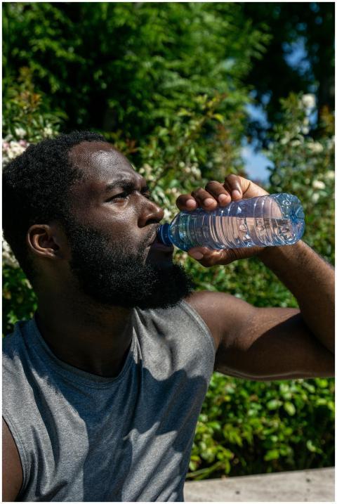 Athletic man drinking water from plastic bottle in