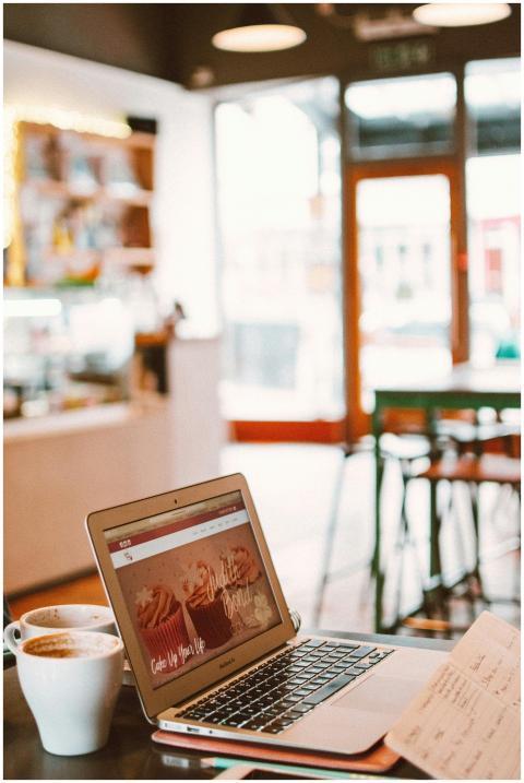 A cozy café setting with a laptop, coffee, and not