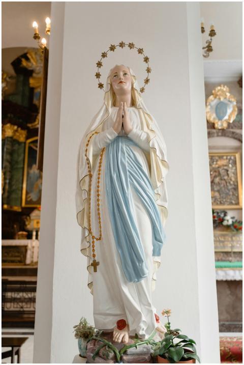 A serene statue of the Virgin Mary with a rosary,