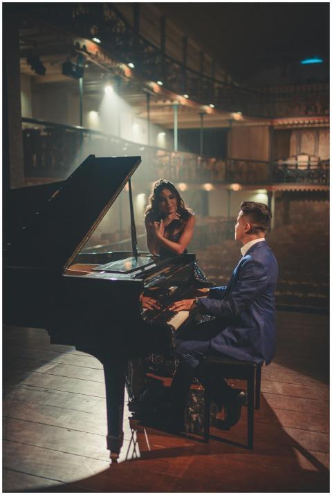 A man playing the piano with a woman nearby in an