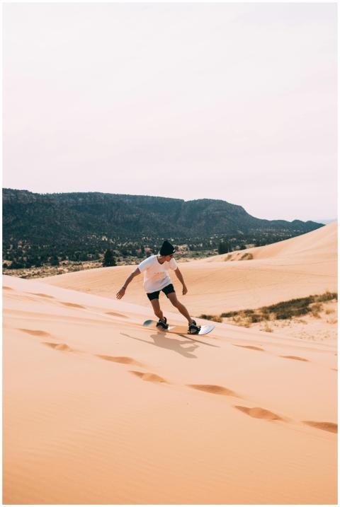Young person sandboarding on Utah's dunes with sce