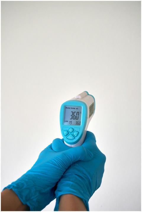 Close-up of gloved hands holding an infrared therm