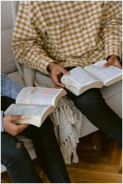 Two individuals sitting on a sofa reading and disc