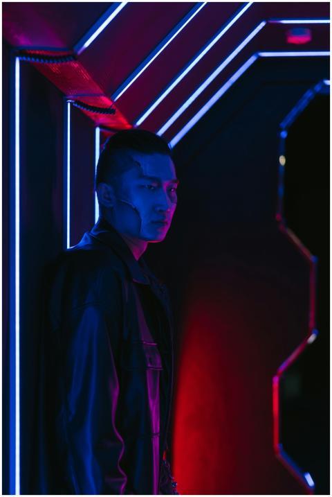 A man stands in a futuristic setting illuminated b