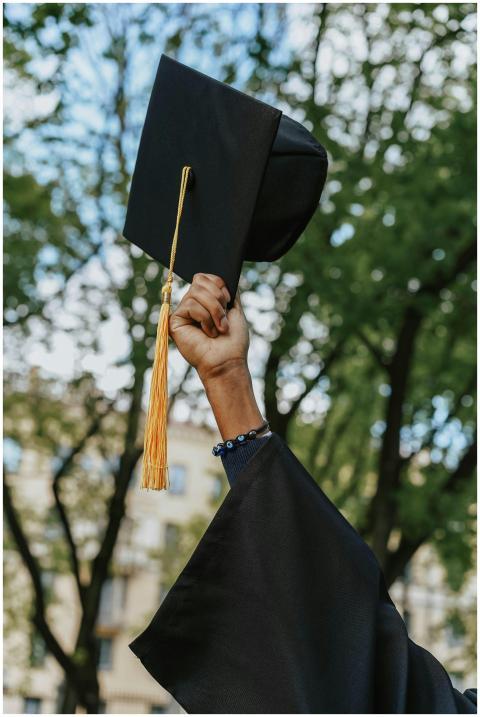 A close-up of a hand raising a graduation cap in c