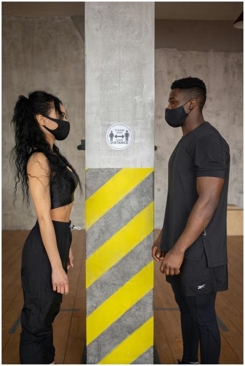 Side view of woman and black male in medical masks