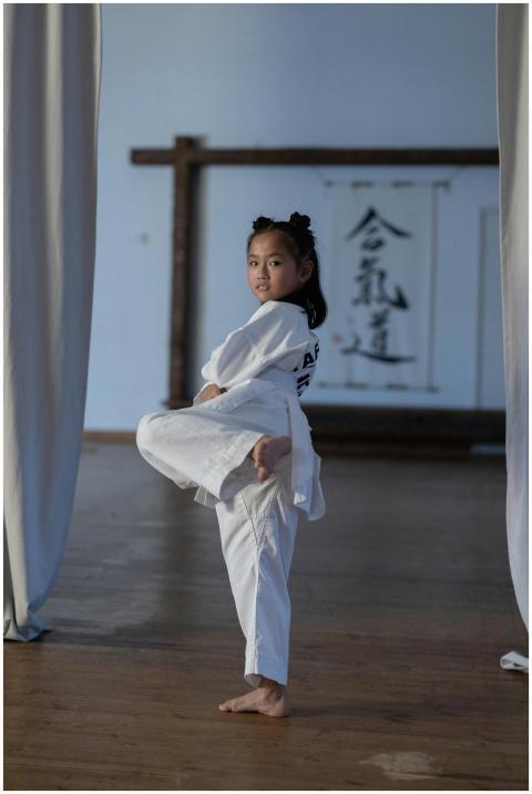 A young girl practicing taekwondo indoors, perform