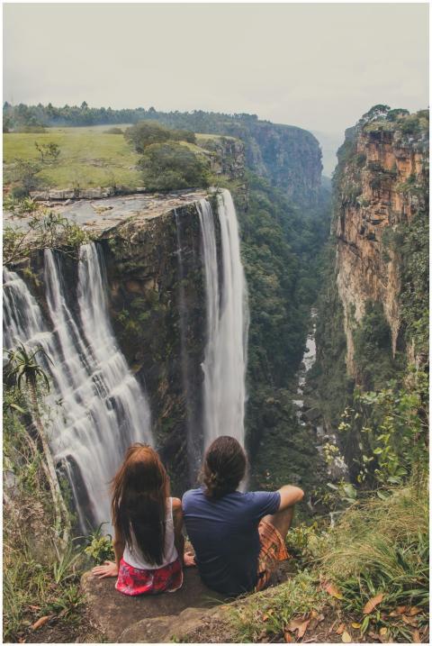 Couple sitting near a majestic waterfall enjoying