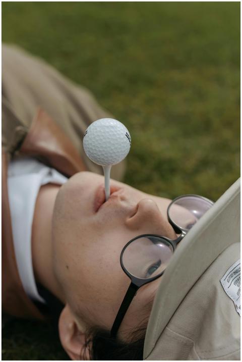 Person lying on grass balancing a golf ball on the