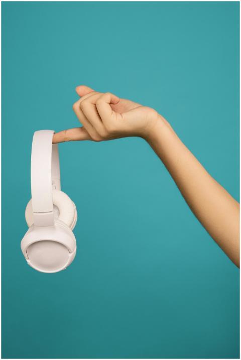 A hand gracefully holds wireless headphones agains