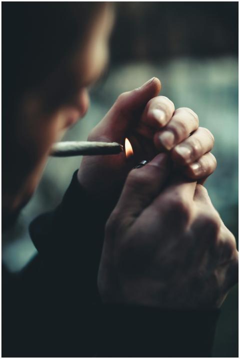 Close-up photo of a person lighting a cigarette wi