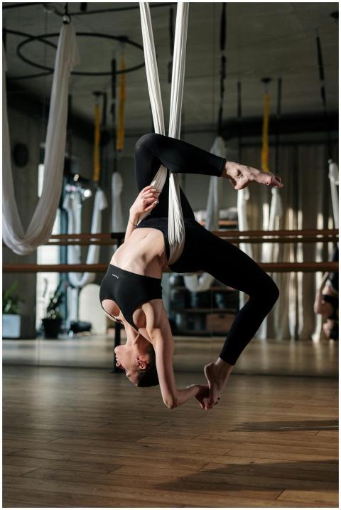 Woman practicing aerial yoga in studio, displaying