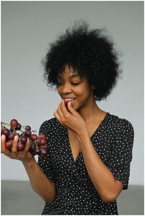 Portrait of a woman joyfully eating grapes. Perfec