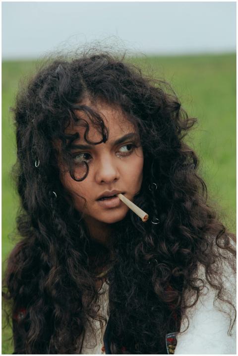Portrait of a woman with curly hair holding a ciga