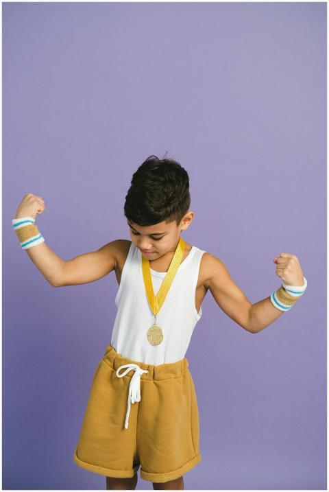 A confident young boy shows off his gold medal, po