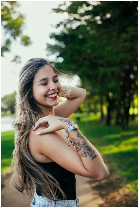 Young woman with tattoo smiling in a park during a