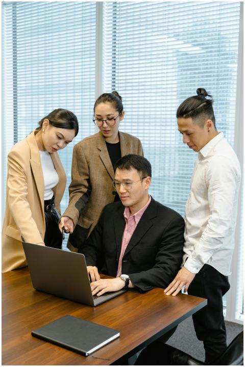 A diverse team collaborates around a laptop in a m