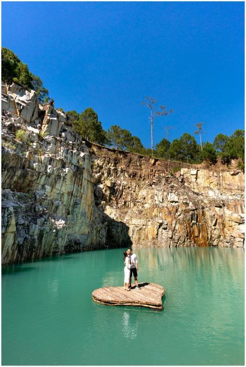 A couple embraces on a rock in a picturesque lake