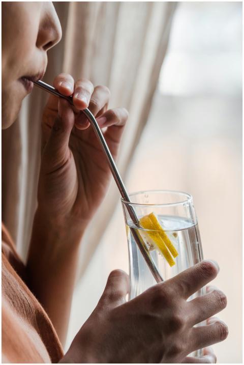 Close-up of a person sipping lemon water through a