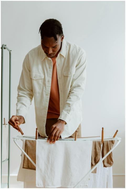 A man hangs laundry on a dryer in a clean, minimal