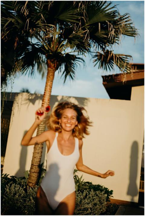 Smiling woman in a white swimsuit enjoys a sunny d