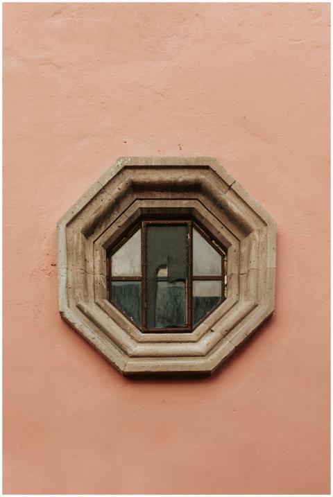 A unique octagonal window set in a pink wall facad