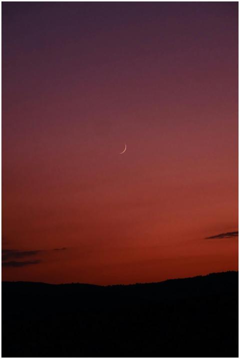 A tranquil view of a crescent moon against a gradi