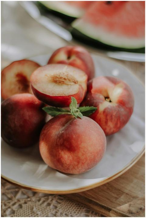 A close-up of ripe peaches on a plate with a water