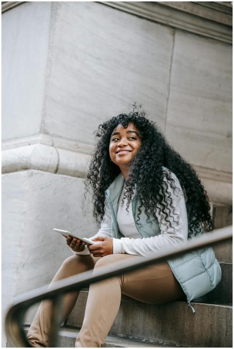 Happy young woman with curly hair sitting on steps
