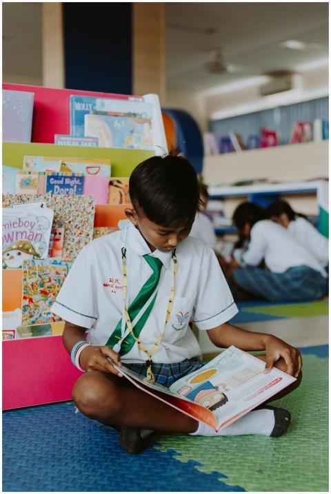 A young student reads intently on the library floo