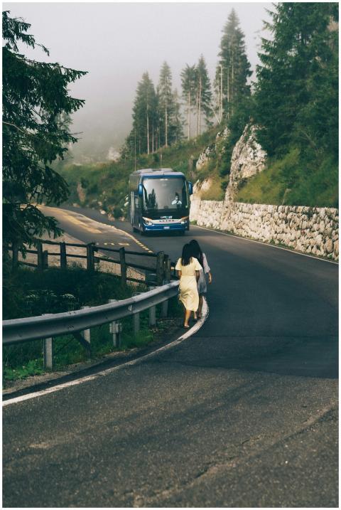 A blue bus on a misty mountain road with two trave
