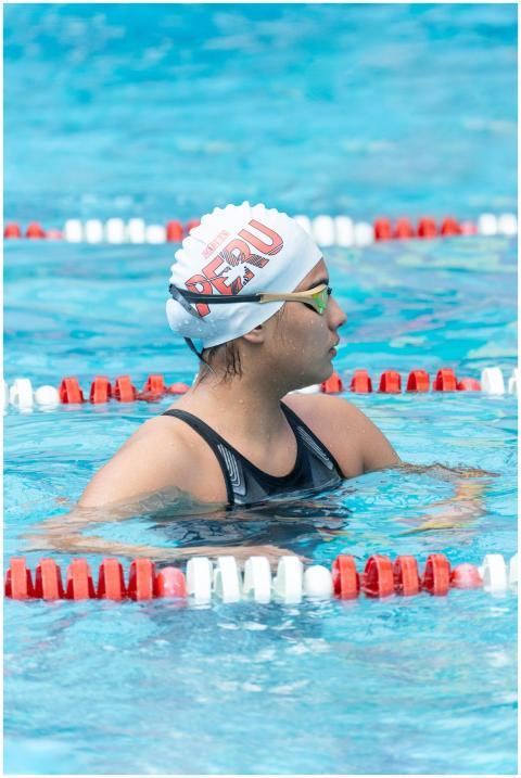 Female swimmer in pool wearing Peru swim cap. Focu