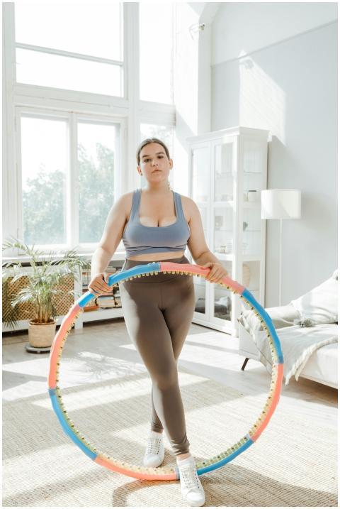 Confident plus size woman exercises with a hula ho