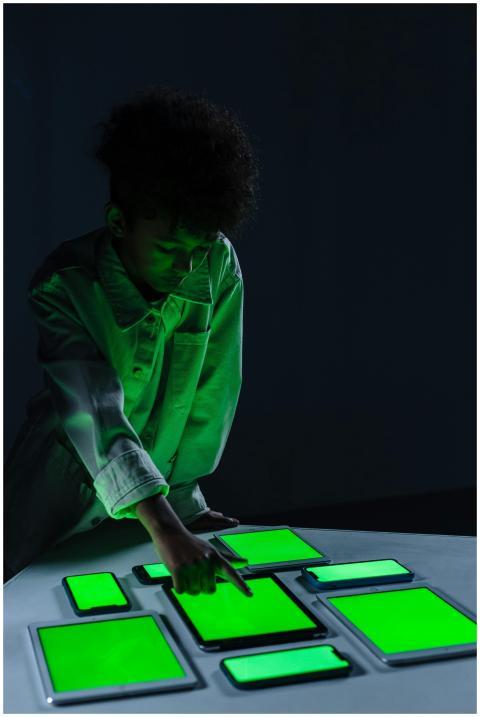 A child in a dark room interacts with several digi