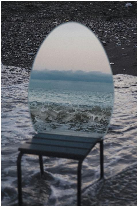 An artistic mirror reflecting ocean waves on the b