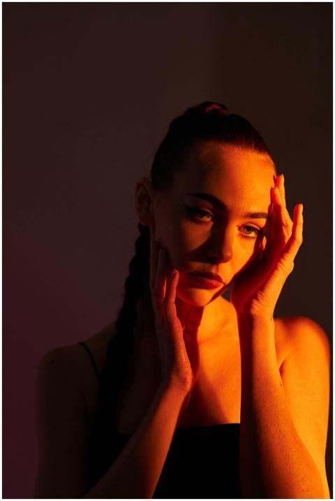 A woman poses in warm dramatic lighting, conveying