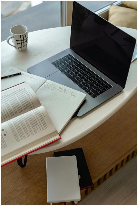 A cozy indoor workspace featuring a laptop, open b