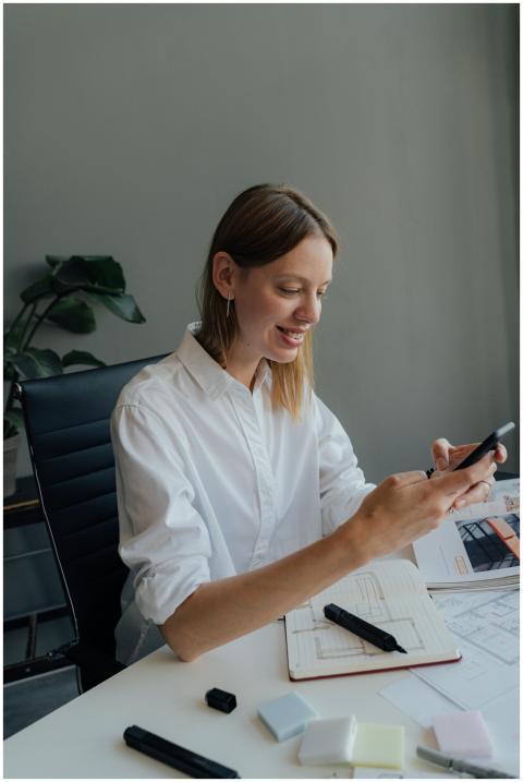 A woman working at a desk with a smartphone and ar