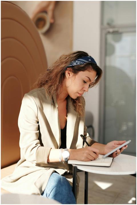 Confident businesswoman writing notes while using