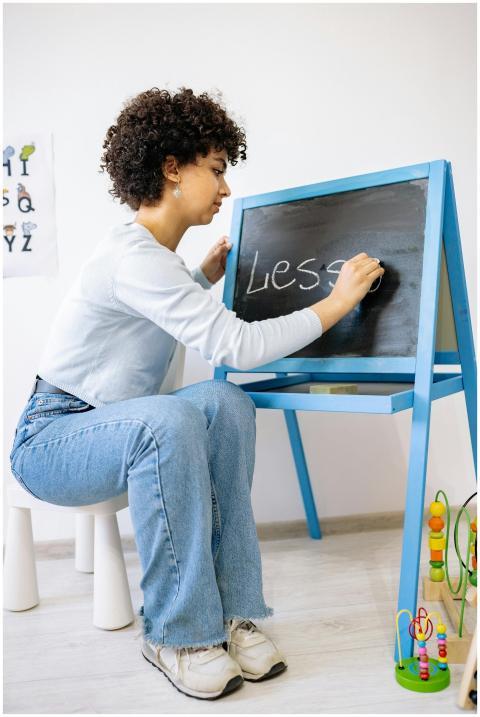 A preschool teacher writing on a blackboard in a c